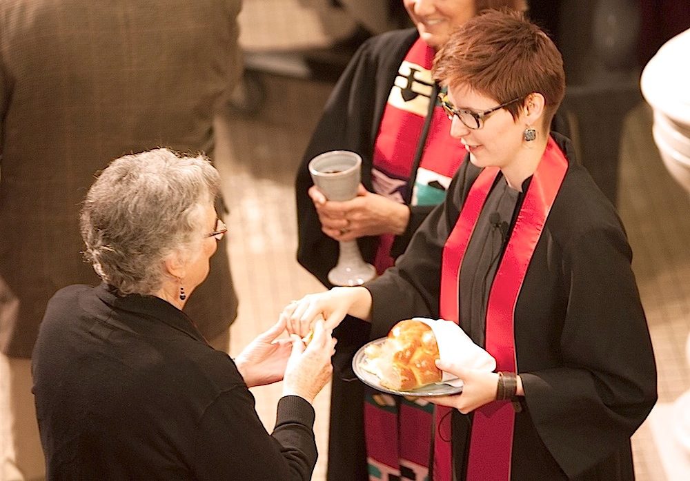 A woman is handing a woman a piece of bread.