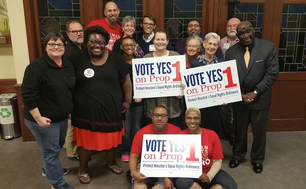 A group of people posing for a photo holding signs.