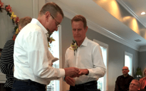 Two men are exchanging rings at a wedding.