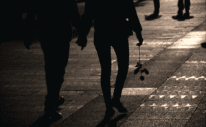 A couple walking down the street holding hands.