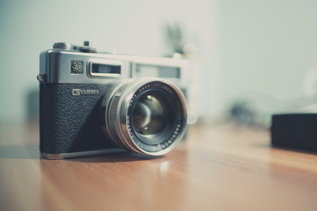 A vintage camera sits on a wooden table.