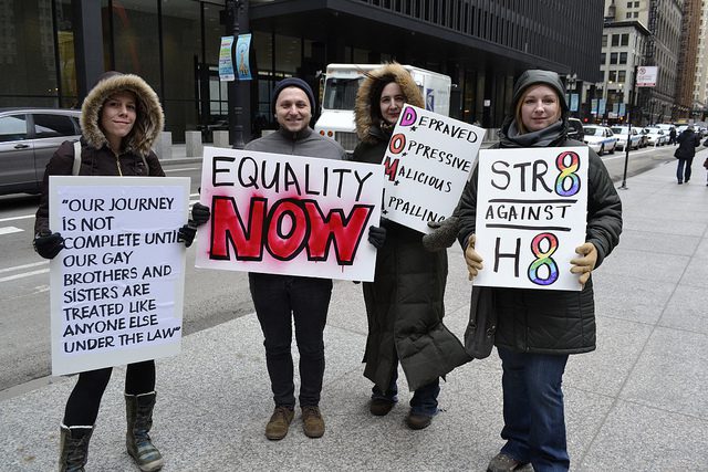 A group of people holding signs that say equality is now.