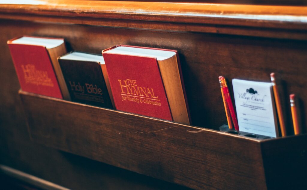 A wooden shelf with books and pencils on it.