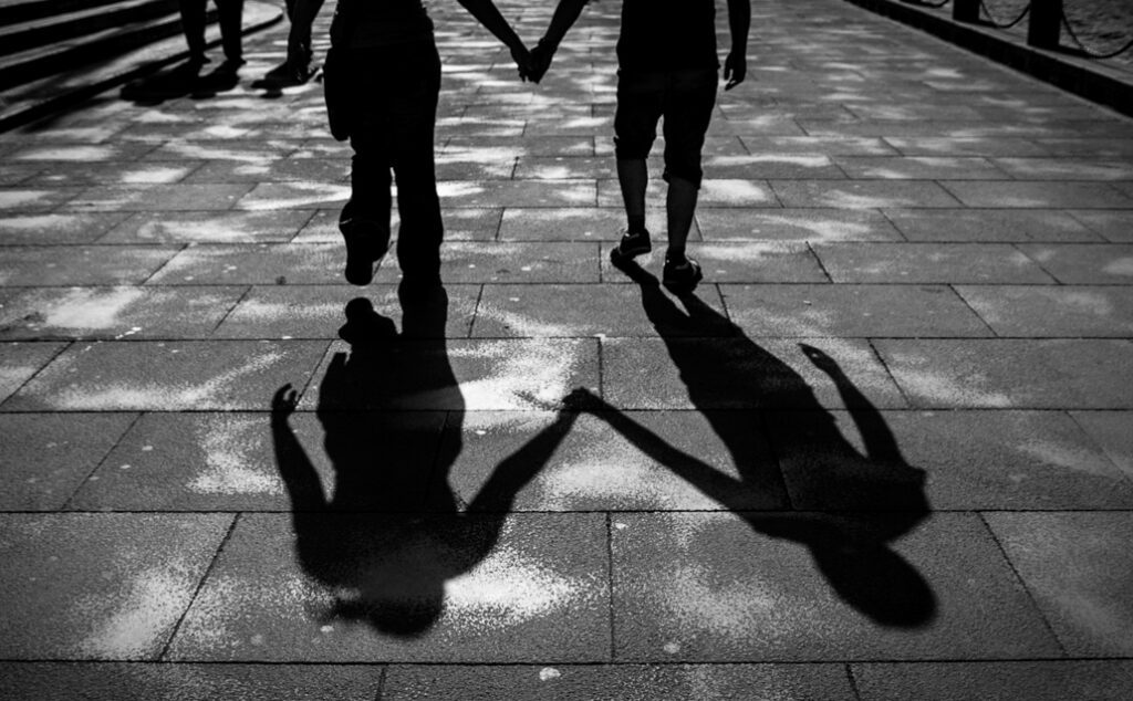 Two people holding hands on a bridge.