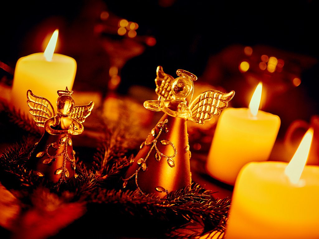 Two angels and candles on a table.