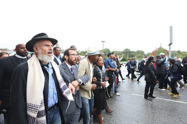 A group of people standing in a line with hats and scarves.