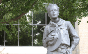 A statue of a boy scout in front of a building.