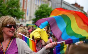 A woman waving a rainbow flag in a crowd.