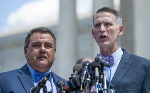 Two men standing in front of microphones in front of the supreme court.