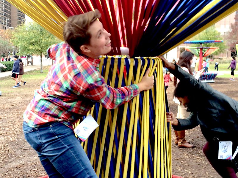 A group of people playing with a colorful sculpture in a park.