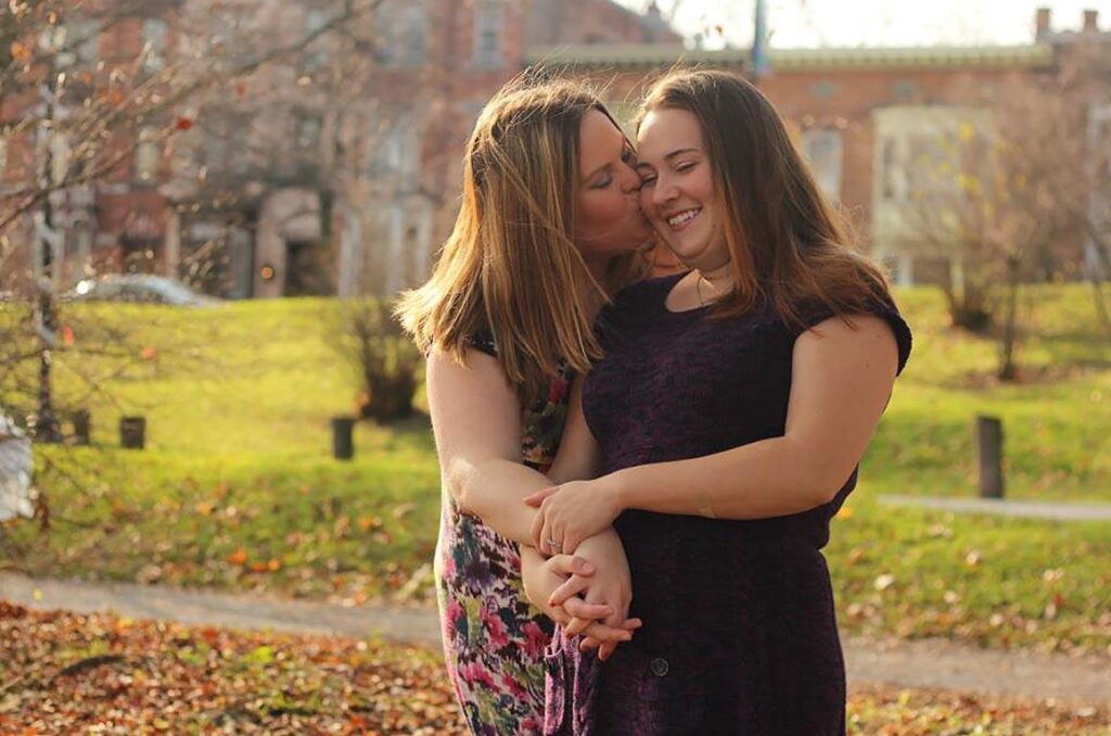 Two women hugging in a park.