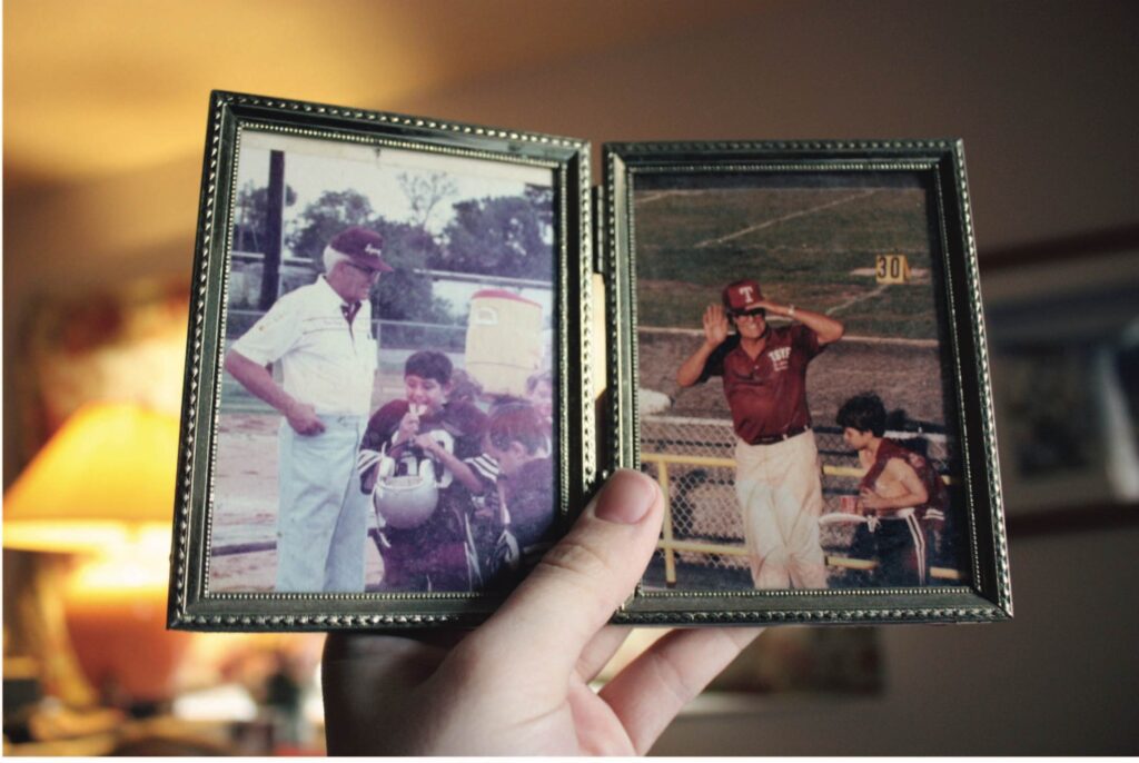 A person holding up two pictures of a man and a woman.