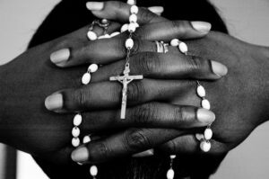Black and white photo of a person holding a rosary.