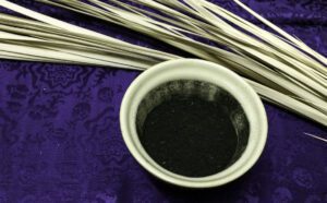 A bowl of black powder on top of a purple cloth.