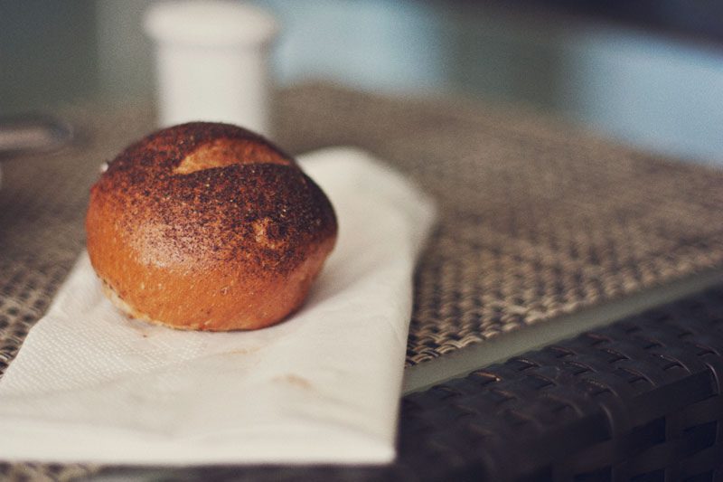 A brown bun on a napkin on a table.