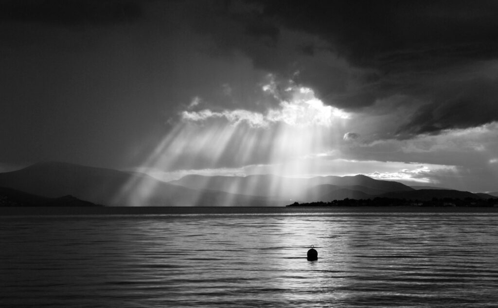 A black and white photo of a stormy sky over a body of water.