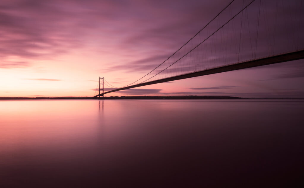 A bridge over a body of water at sunset.