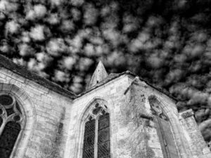 A black and white photo of a church with a cloudy sky.