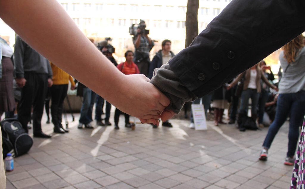 A man and woman holding hands in front of a crowd of people.