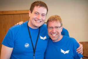 Two men in blue shirts posing for a photo.