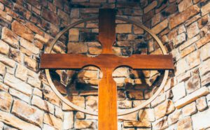 A wooden cross sits on top of a stone wall.