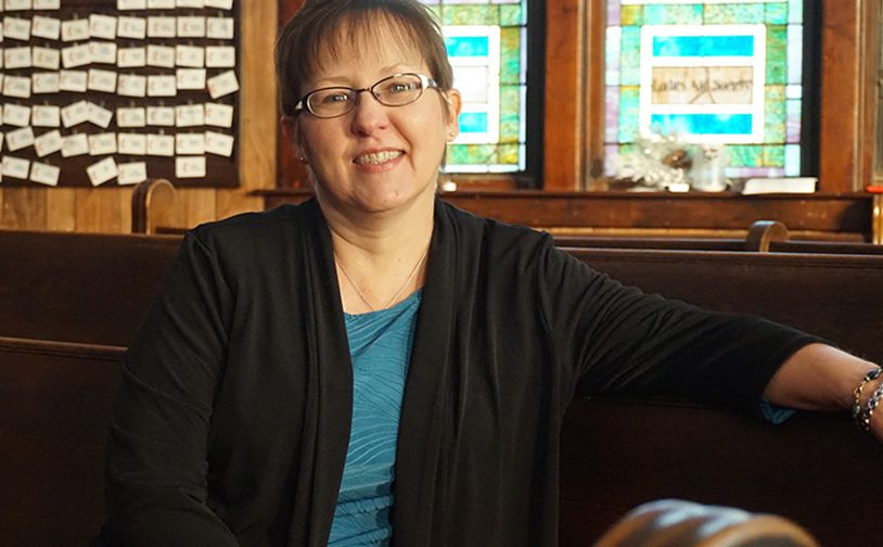 A woman sitting on a bench in a church.