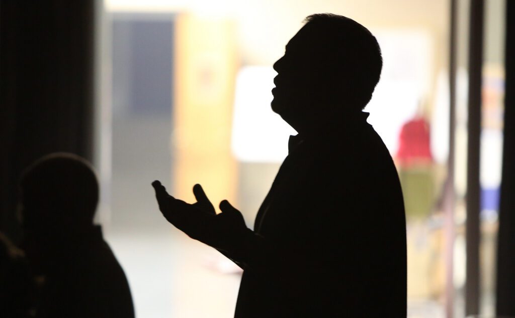 A man is silhouetted in front of a door.