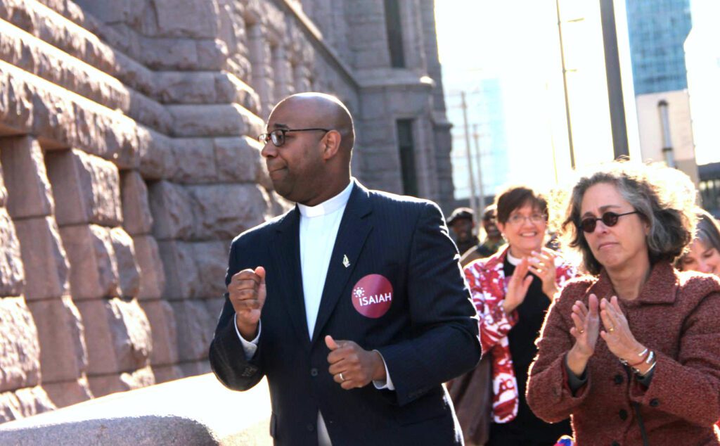 A group of people clapping in front of a building.