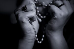 A black and white photo of a woman holding a rosary.