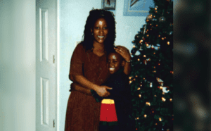 A woman and a child standing in front of a christmas tree.