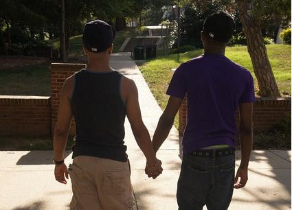 Two men holding hands on a sidewalk.