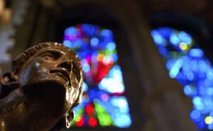 A statue of a man in front of stained glass windows.