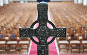 A cross sits on a red carpet in a church.