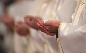 A group of priests in white robes clapping their hands.