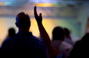 A group of people raising their hands in a church.