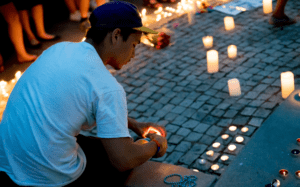 A man sits on the ground with candles in front of him.