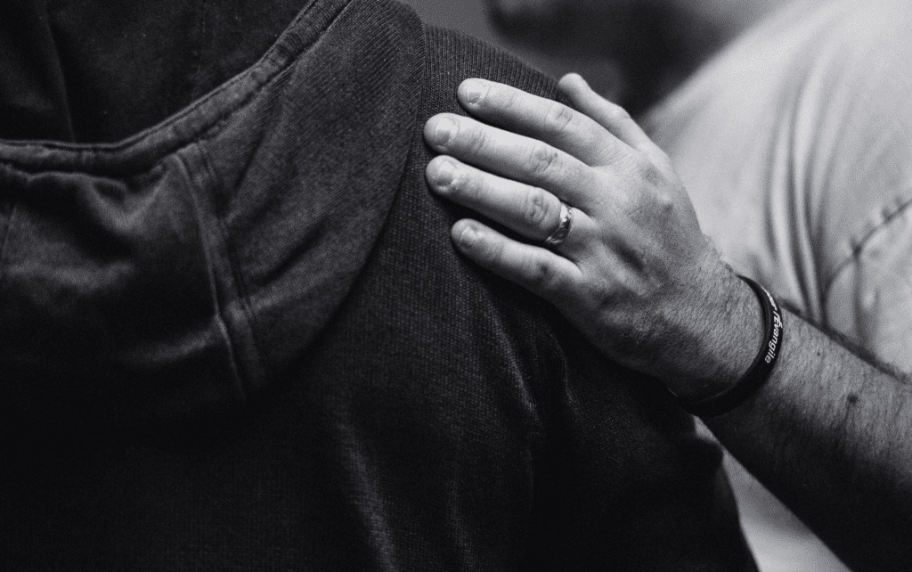 A black and white photo of a man hugging another man.