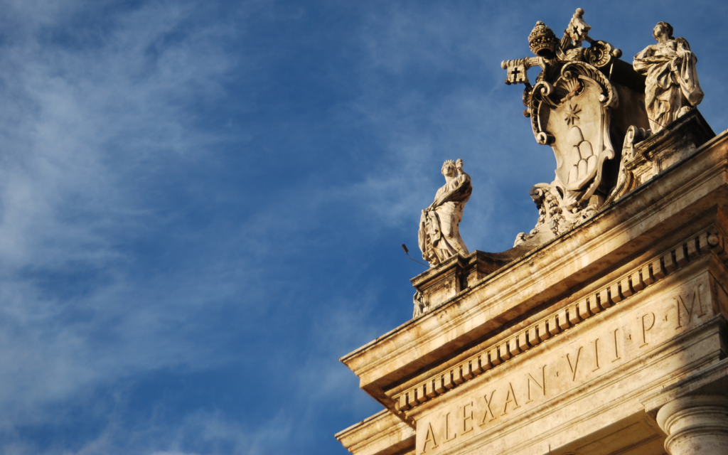 A statue on top of a building against a blue sky.