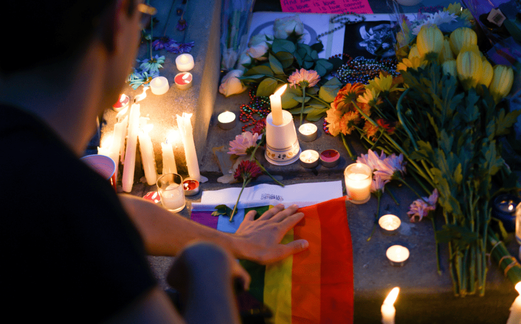 A man is laying flowers at a candlelit vigil.