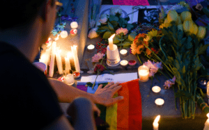 A man is laying flowers at a candlelit vigil.