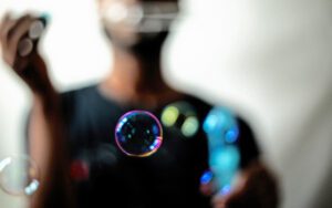 A man blowing bubbles in front of a white background.