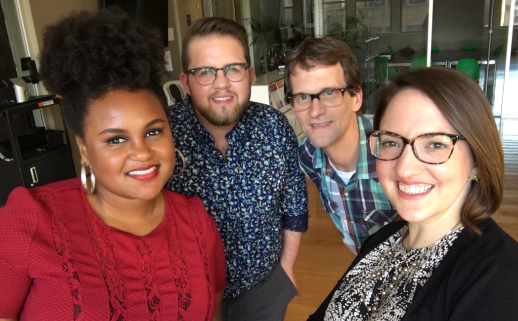 Four people posing for a photo in an office.