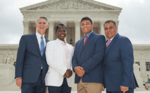 Four people standing in front of the supreme court building.