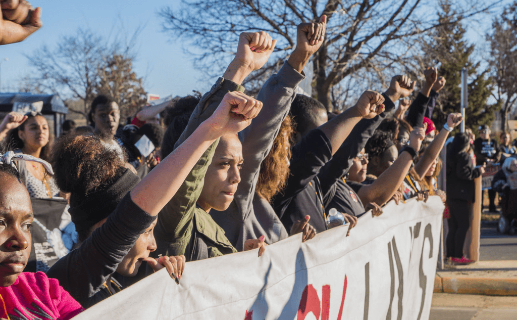 A group of people holding up their fists at a protest.