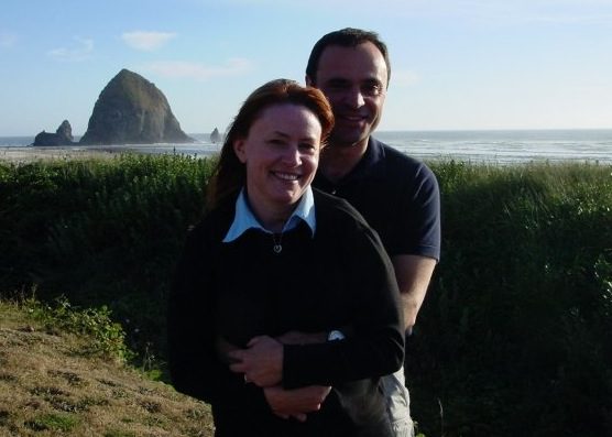 A man and woman posing for a picture in front of the ocean.