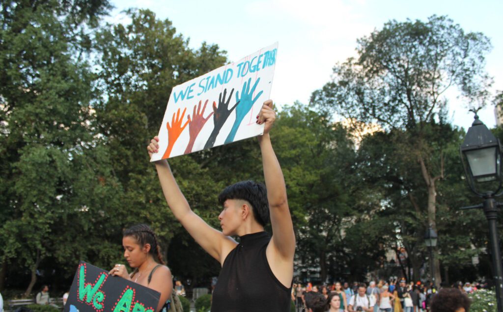 A woman holding up a sign in front of a crowd.