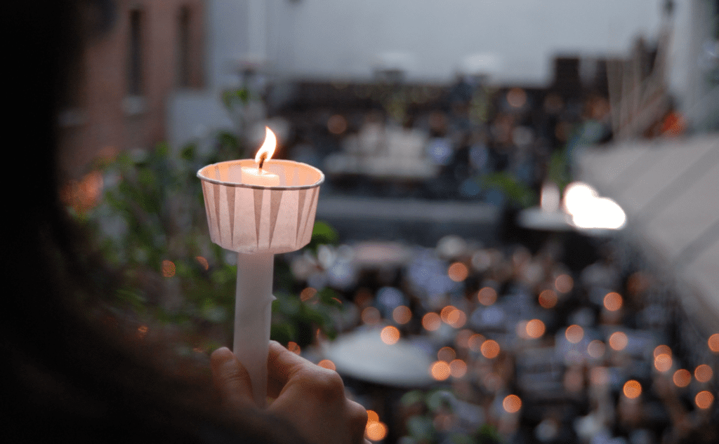 A person holding a candle in front of a crowd of people.