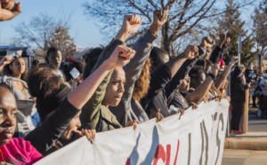 A group of people holding up a banner with their fists up.