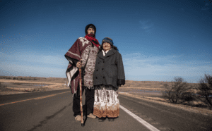 A man and woman standing on the side of a road.