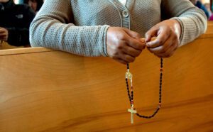 A woman holds a rosary in a church.